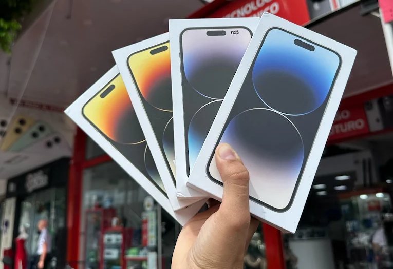Cuatro cajas de iPhone nuevos en la mano frente al local de Aló! Central Móvil